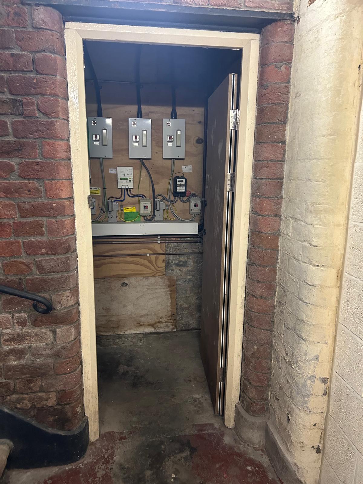 Exposed electric meter cupboard before fire door installation in a Liverpool communal area