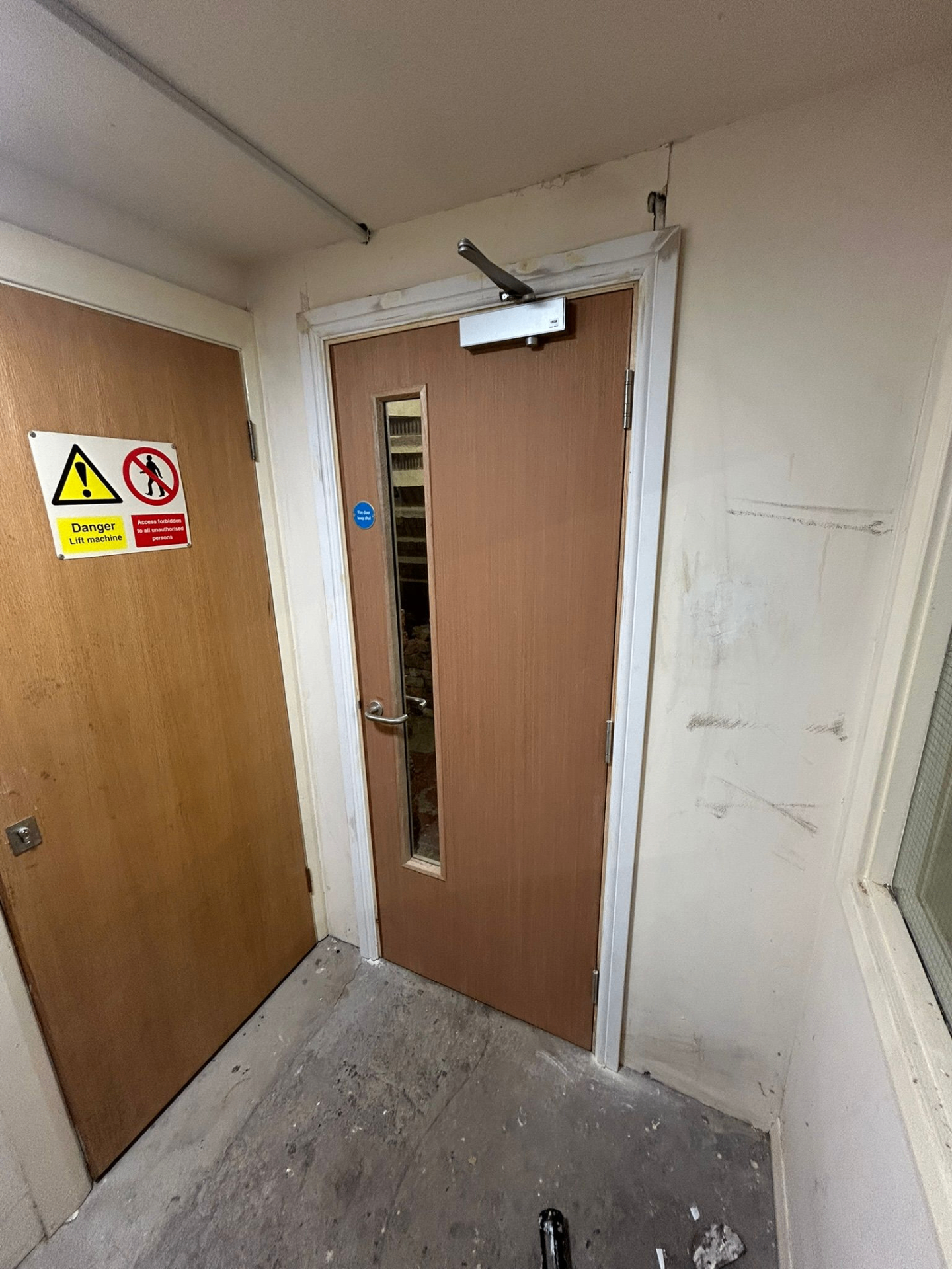 Fire door inspection of a certified communal fire door with overhead closer, signage and intumescent seals, Liverpool